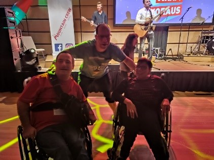 Bild: 2 Personen im Rollstuhl und eine Person in der Mitte auf der Tanzfläche